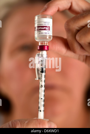 Una femmina senior prepara una siringa da insulina, che è usato per trattare il diabete. Foto Stock