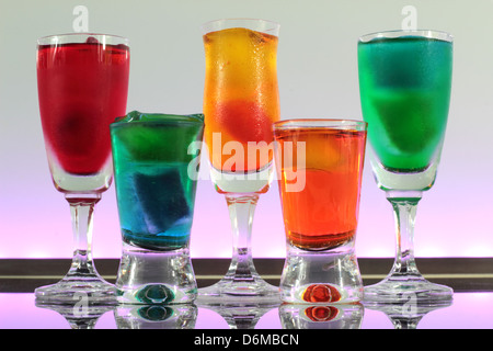 Dettaglio di una linea di cocktail colorati in appoggio sulla barra con illuminazione a led in un club Foto Stock