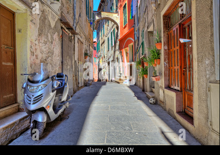 Scooter sorge sulla strada stretta tra vecchie case residenziali a Ventimiglia, Italia. Foto Stock