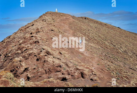 Un uomo cammina dalla cima del vulcano, Montana Roja, una destinazione popolare per i vacanzieri in Playa Blanca, Lanzarote. Foto Stock