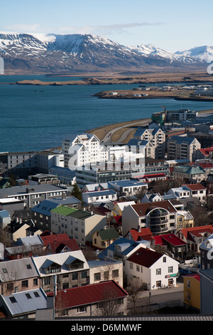 Le strade e gli uffici e le case del quartiere finanziario di Reykjavik, Islanda. Sfondo con mare e neve montagna sormontata. Foto Stock