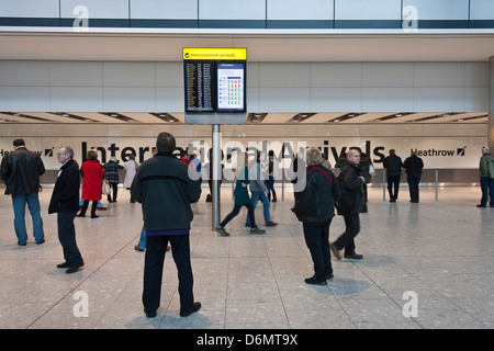 Il terminale 5, l'aeroporto di Heathrow di Londra. Gli arrivi internazionali area con informazioni sullo schermo. Foto Stock