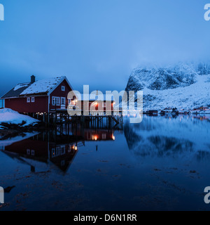 Tradizionale cabina Rorbu riflette nel fiordo nella luce della sera, Valen, Reine, Moskenesøy, Isole Lofoten in Norvegia Foto Stock