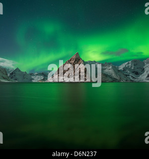 Aurora Boreale - Northern Lights riempire il cielo sopra Olstind picco di montagna e riflettere nel fiordo, Toppøya, Isole Lofoten in Norvegia Foto Stock
