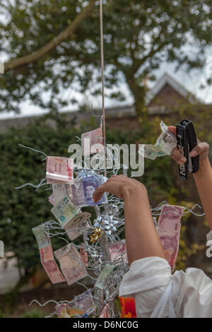 La raccolta di fondi per contribuire a sostenere il tempio Buddhavihara, Kings Bromley. Una donna è visto circa per la pinzatura di un cinque pound nota da aggiungere alla collezione. Foto Stock