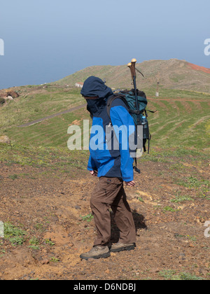 Escursionista maschio proteggendo la sua faccia da vento mentre si cammina per un sentiero in Teno alto altopiano di montagna a Tenerife Spagna Foto Stock