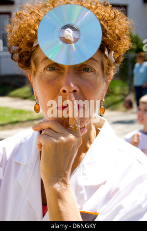 Donna matura in medico il mantello bianco costume e disco a specchio sulla fronte. MayDay Parade Festival e Minneapolis Minnesota MN USA Foto Stock