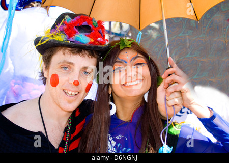 Donna asiatica e uomo bianco età 23 in costume avendo divertimento che porta ombrellone. MayDay Parade Festival e Minneapolis Minnesota MN USA Foto Stock