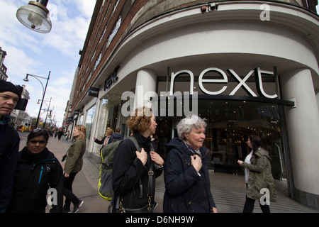 Un acquirente passa davanti al negozio Next di Oxford Street, Londra, illustrando la continua importanza della moda di strada britannica in una delle destinazioni commerciali più trafficate della capitale. Foto Stock