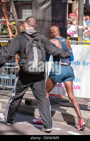 Londra, East Smithfield, 21 aprile 2013. Mo Farah, somale nato e Team GB di Olimpiadi doppia medaglia nel 5,000m e 000m a Londra 2012, termina la sua gara come previsto, appena prima di miglio 13 e viene portato via da un Marshall. Prima della gara Farah aveva detto che egli ha voluto restare con la Elite Uomini Maratona fino a metà strada e ha fatto proprio questo. Foto Stock