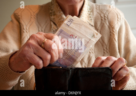 Donna anziana donna anziana mettere venti pound note in borsa Foto Stock