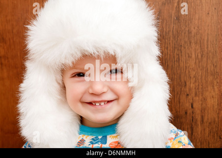 Closeup ritratto di bambina in grande bianco inverno hat grande sorriso Foto Stock