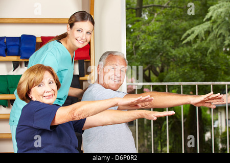 Felice fisioterapista con gli anziani facendo esercizi di fitness per le spalle Foto Stock