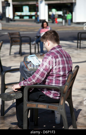 Brixton Windrush Square - Uomo di lettura dispositivo Kindle a Lambeth - London REGNO UNITO Foto Stock