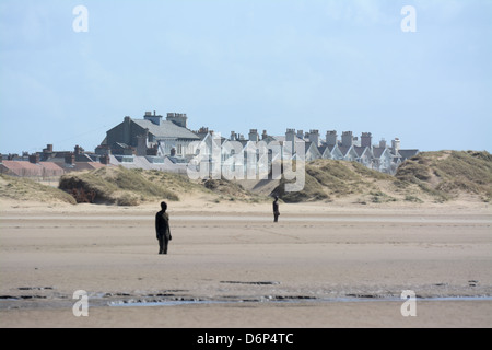 Antony Gormley è un altro posto statue sulla spiaggia a Crosby con case in backgroumd Foto Stock