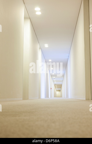 A basso angolo di visione di un lungo corridoio bianco in un hotel, la profondità di campo Foto Stock