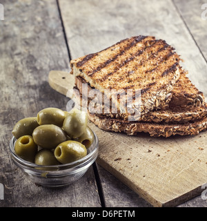 Pane tostato e olive sulla tavola in stretta fino Foto Stock