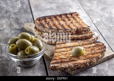 Pane tostato e olive sulla tavola in stretta fino Foto Stock