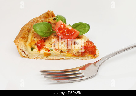 Fetta di formaggio, pomodori e basilico quiche su una piastra con una forcella Foto Stock