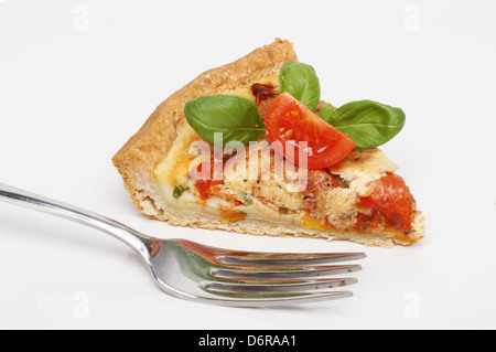 Fetta di pomodoro, formaggio e basilico quiche su una piastra con una forcella Foto Stock