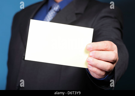 Primo piano del fustellato nota business card o un cartello in mano d'uomo sfondo blu Foto Stock