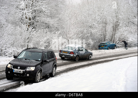 Veicoli che passano un crash car che a sinistra la strada in condizioni di neve vicino a Stroud GLOUCESTERSHIRE REGNO UNITO Foto Stock