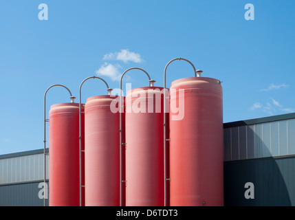 Quattro industriali silos rosso appartenente ad una fabbrica di cemento Foto Stock