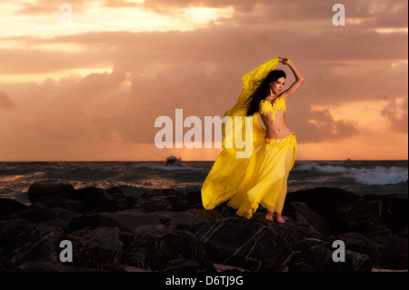 Una danzatrice del ventre in Costume Giallo sulla spiaggia di Sunrise Foto Stock