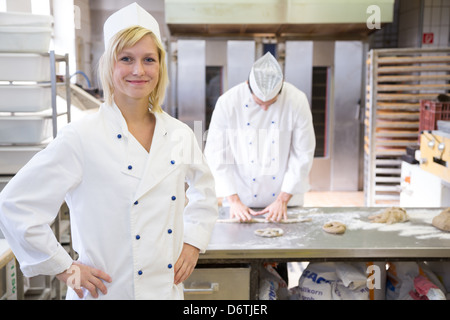 Baker in posa di panificio o bakehouse. Un altro baker sta lavorando in background Foto Stock