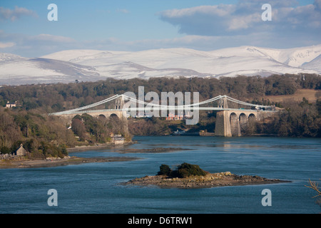 Thomas Telford di Menai Bridge di sospensione oltre il Menai Strait con montagne innevate di Snowdonia dietro Anglesey North Wales UK Foto Stock