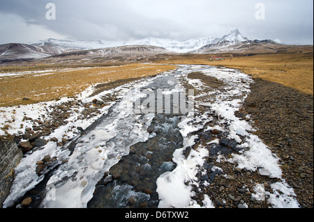 Un piccolo fiume galleggiando giù dalle montagne in Islanda in inverno Foto Stock