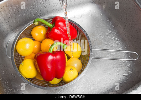 Colorate di lavaggio di frutta e verdura in il lavandino della cucina. Foto Stock