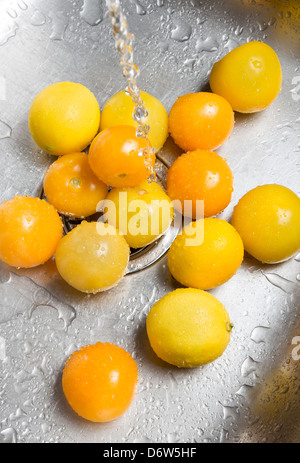 Giallo di lavaggio i pomodori e i limoni nel lavello. Foto Stock