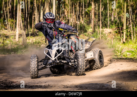 Il corridore di ATV prende una svolta durante una gara su un terreno polveroso. Foto Stock