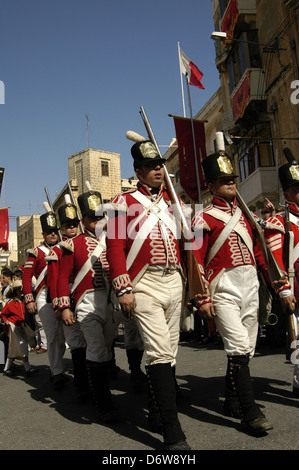 Gli uomini maltesi vestiti come soldati della guarnigione francese prendono parte alla rievocazione storica dell'assalto dei francesi sotto Napoleone (1798-1800) e all'arrivo degli inglesi che hanno aiutato a battere i francesi durante il Carnevale maltese nell'isola di Malta Foto Stock