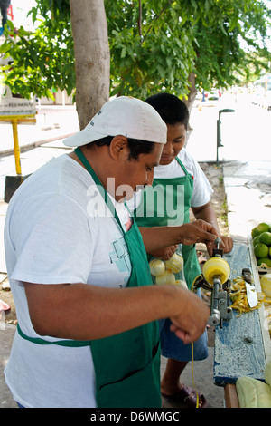 Uomo che utilizza un azionati a mano-frutta macchina pelatrice presso il suo stand di frutta su Avenida Tulum in downtown, Cancun Quintana Roo, Messico Foto Stock