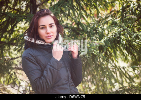 Giovane ragazza in piedi vicino a rami di abete rosso nella giornata di sole Foto Stock