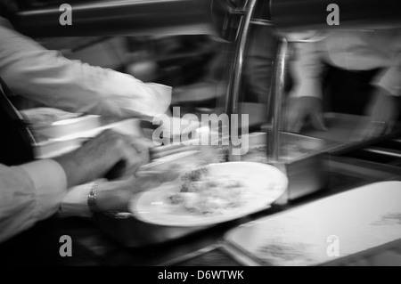 Immagine sfocata dei ristoratori che servono cibo caldo in una mensa. Foto Stock