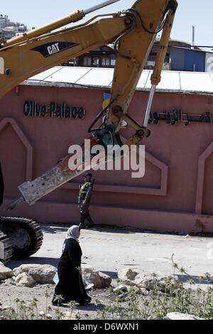 Gerusalemme, Territorio palestinese. 24 Aprile, 2013. Una donna Palestinese cammina davanti a un bulldozer israeliano come si abbatte una casa palestinese a Gerusalemme il 24 aprile 2013. Comune di Gerusalemme demolito inizio oggi tre appartamenti e tre negozi di proprietà di palestinesi Khomeini Hamdan e Kayed Jaradat nel quartiere Khelat al-Ein nel villaggio di al-Tur, sotto il pretesto della costruzione senza un permesso (credito Immagine: © Sliman Khader/immagini APA/ZUMAPRESS.com) Foto Stock