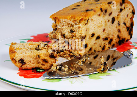 Uva sultanina pan di spagna su una piastra con un coltello da dolce. Foto Stock