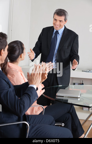 Manager battendo le mani per il consulente dopo una presentazione in ufficio Foto Stock