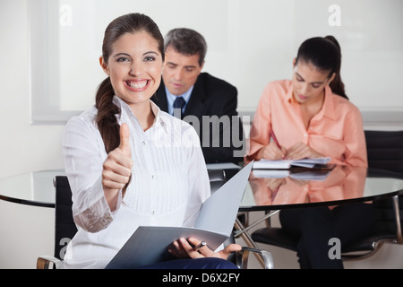 Felice busines donna con file in office mentre tiene il suo pollice in alto Foto Stock