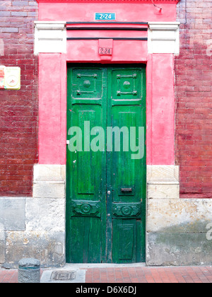 Il verde di porte in legno e rosa e rosso mattone edificio, Bogotà, Colombia Foto Stock