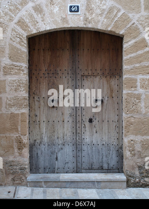 Vecchio brown porta a Valldemossa, Spagna, incorniciato da un muro di pietra. Foto Stock