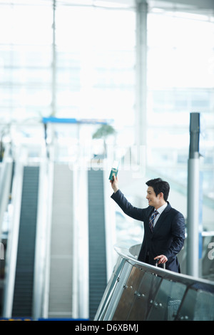 Un imprenditore in possesso di un passaporto agitando la mano all'aeroporto Foto Stock