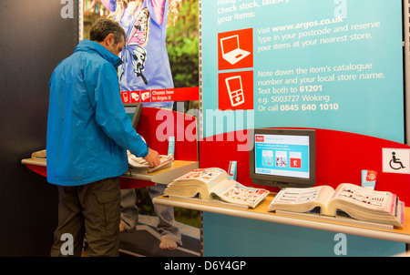 Uomo che guarda attraverso il catalogo in Argos store, England, Regno Unito Foto Stock