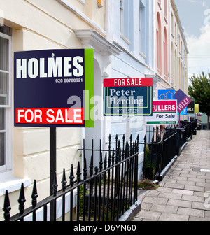 Fila di case inglesi con in vendita segni infront di ciascuno Foto Stock