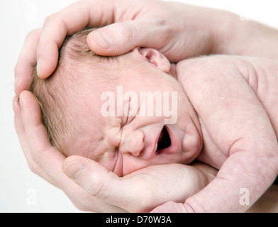 Una settimana di età bambino piangere ed essere cullato nel Padre con le mani in mano. Foto Stock