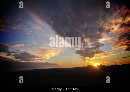 Tramonto in Moody Sky - un drammatico tramonto su una spiaggia scura. Foto Stock