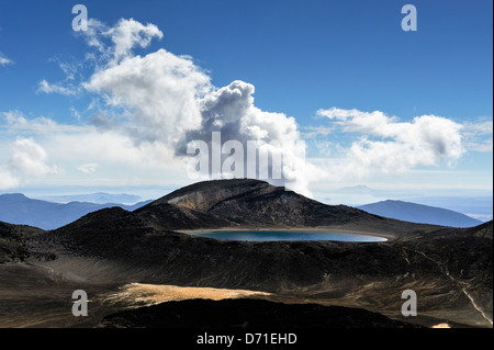 Fumo dal Te Maari cratere, Monte Tongariro con lago blu in primo piano. Tongariro Alpine Crossing, Nuova Zelanda Foto Stock